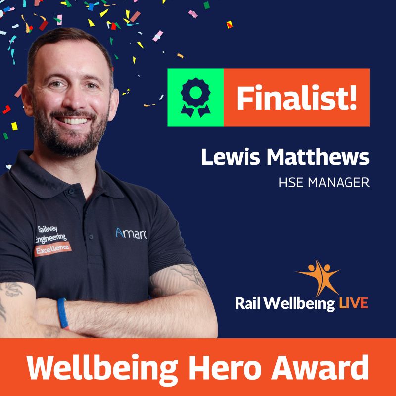 A vibrant graphic celebrating Lewis Matthews as a finalist for the Wellbeing Hero Award at Rail Wellbeing LIVE. Lewis, an HSE Manager at Amaro, is shown smiling and wearing a black polo with the Amaro logo and ‘Railway Engineering Excellence’ text. The background features festive multicolored confetti and includes a badge with the word ‘Finalist!’ in orange and green. Below, a large orange banner highlights the ‘Wellbeing Hero Award’ with the Rail Wellbeing LIVE logo adjacent.